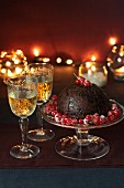Christmas Pudding mit roten Johannisbeeren und zwei Gläsern Weißwein