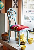 A Baroque-style chair with a colourful knitted cushion cover