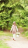 Kleines Mädchen mit Maiglöckchen im Korb auf Waldweg