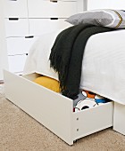 Storage for blankets and pillows in large drawers below bed; chest of drawers in background