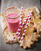 Butter biscuits with colourful sugar sprinkles next to a strawberry milkshake