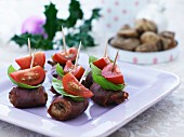 Meatballs wrapped in ham with basil and tomatoes on sticks