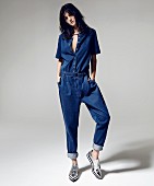 A young woman wearing a denim jumpsuit and flat lace-up shoes