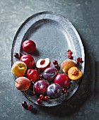 Fresh plums, peaches and cherries on a metal tray