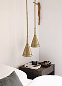 Pendant lamps with brass lampshades and bedside table next to bed