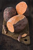 Süßkartoffeln auf Holzbrett, teilweise geschält