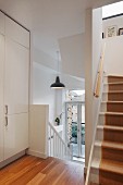 Stairwell with white wooden treads, runner and white fitted cupboard on landing