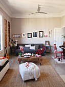 Loungebereich mit weißem Hocker, Bodentisch aus Holzpalette und graue Couch in offenem Wohnzimmer mit traditionellem Flair