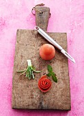 Homemade vegetable flowers, mint leaves and tomatoes on a wooden chopping board
