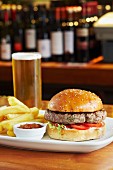 A burger with chips, tomato sauce and a pint of beer
