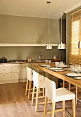 Festively set dining table with tall upholstered chairs and simple kitchen counter in background