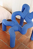 Designerstuhl aus blauen Polsterröhren auf Terracottafliesen