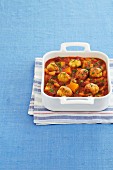 A bake with small dumplings, tomatoes, sweet potatoes and parsley