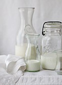 Various types of milk in different bottles on a white tablecloth