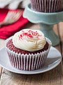A Red Velvet cupcake with white frosting