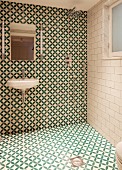 Modern bathroom with floor-level shower and green and white, geometric tiles