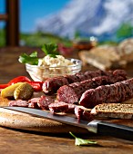 Supper with Kaminwurzen (South Tyrolean smoked sausages), horseradish and Vinschgau bread against a mountain backdrop