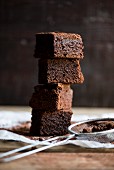 A stack of brownies and a sieve with cocoa powder