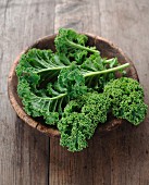 Green kale in a wooden bowl on a wooden surface