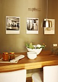Wooden dining table in front of black and white photos on painted wall