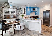 Küche mit Kommode, weissen und blauen Schränken sowie Esstisch