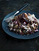 Radicchio risotto with onion confit on a dark plate with a fork