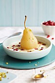 A poached pear in a creamy sauce with pomegranate seeds