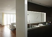 Hatch above narrow counter in designer kitchen with view into white-furnished interior