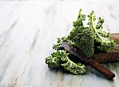 Fresh green kale leaves on a chopping board with a knife