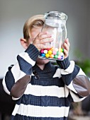A little boy holding a jar of sweets