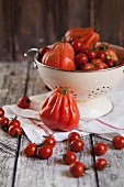 Beefsteak tomatoes and cherry tomatoes in a colander on a wooden surface