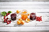 Cherry jam and cherries, apricot jam and apricots, redcurrant jam and redcurrants on a doily