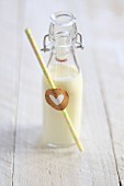 A bottle of milk with a straw and a heart decoration
