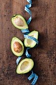Avocado halves and a measuring tape on a wooden surface