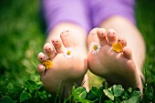 Little girl's toes decorated with daisies and buttercups and with drawn-on smiley faces