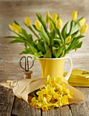 Gelbe Narzissen im Papier und Tulpen im Keramikkrug