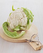 A cauliflower on a light wooden chopping board