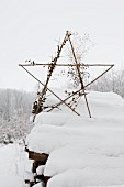 Star made from sticks on top of snow-covered woodpile