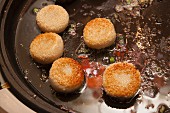 Sesame seed pastries being fried in a pan