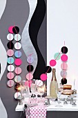 New-Year buffet with sparkling wine, sparklers and garlands of pastel circles decorating wall with grey and black pattern