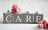 Pink rose buds and tealights on card cubes with decorative lettering spelling 'CARE'