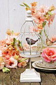 White birdcage ornament, roses and salmon-pink gladioli