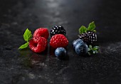 Fresh raspberries, blueberries and blackberries with leaves