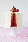 A six-layer sandwich cake with covered with white icing and strawberries, sliced