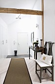 Runner on pale wooden floor, antique chair and console table against wall in hallway