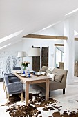 Wooden table, chairs and upholstered bench on animal-skin rug in converted attic