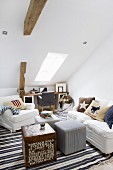 White armchair and sofa around cube table and pouffe in attic room