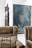Wing-back armchairs with striped pale brown upholstery in front of modern artwork