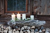 Rustic Advent arrangement on large piece of driftwood on stack of firewood
