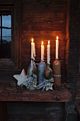 Rustic Advent arrangement with four lit candles in various stoneware bottles